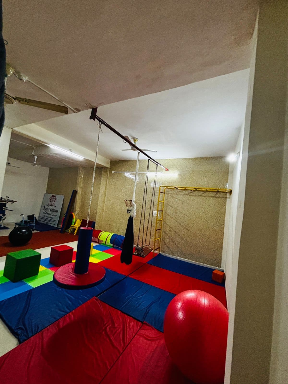 Sensory gym at Naivedyam with colorful foam mats, ceiling swings, and climbing equipment