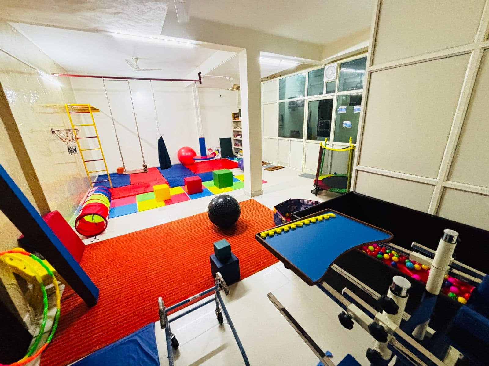 Therapy room with ball pit, crawl tunnel, exercise balls, and ceiling-mounted swings